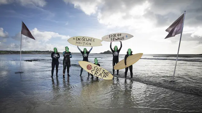 Representatives from Surfers against Sewage protest against sewage discharges at an overflow pipe on Long Rock Beach in Penzance, Cornwall