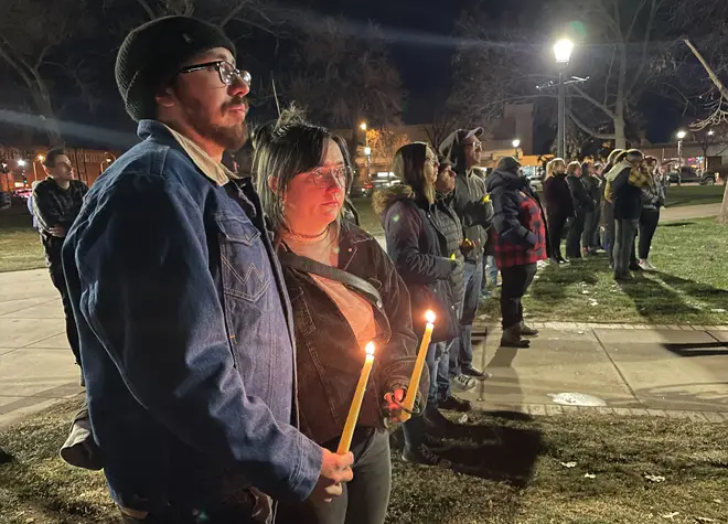People hold candles during a vigil at Acacia Park for the victims of a mass shooting at Club Q
