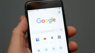 A person holds an iPhone showing the app for Google chrome search engine