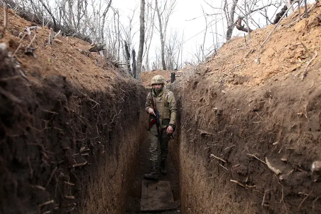 Ukrainian serviceman walks in a trench on the frontline with Russia