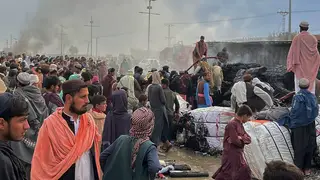 People gather beside a burnt truck caused by Afghan shelling in Chaman, south-west Pakistan