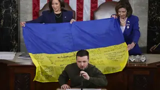 Vice President Kamala Harris and House Speaker Nancy Pelosi react as Ukrainian President Volodymyr Zelensky presents lawmakers with a Ukrainian flag