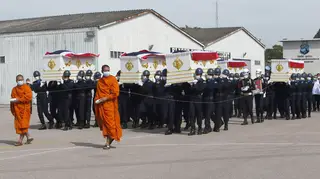 Buddhist monks walk in front of the coffins of the victims of the sinking