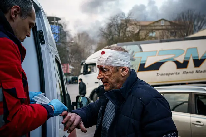 A rescue worker helps an injured man after the shelling
