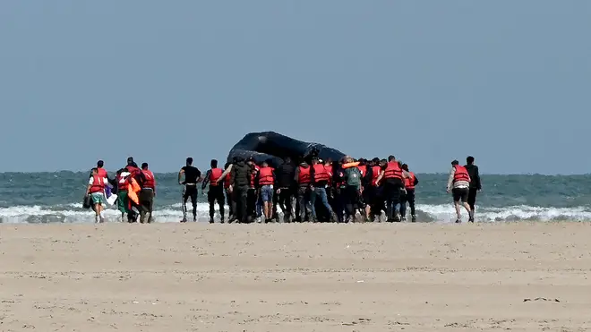 Migrants push an inflatable boat towards water in northern France in August