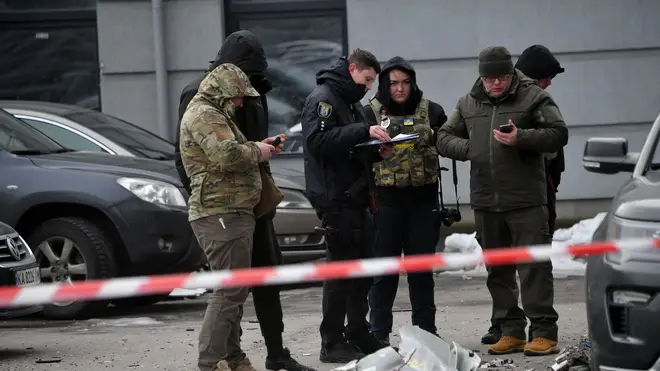 Police experts examine remains of a downed missile which fell on a vehicle parked at a multi storey residential building in Kyiv