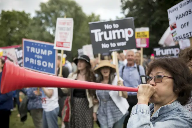 A woman blows a vuvuzela at a Trump protest at Buckingham Palace