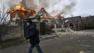 A local resident runs past a burning house hit by Russian shelling in Kherson, Ukraine, on the Orthodox Christmas Eve