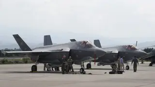 US military personnel work near F-35 fighter jet of the Vermont Air National Guard, parked in the military base at Skopje Airport, North Macedonia, on June 17 2022