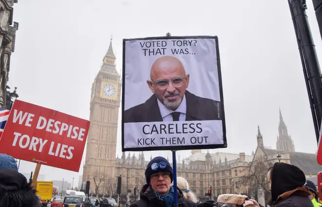 A protester holds an anti-Tory placard with a picture of Nadhim Zahawi