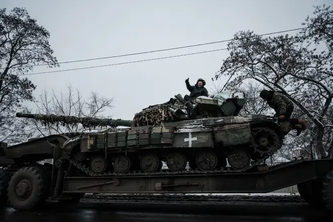 A Ukrainian serviceman waves from atop a main battle tank