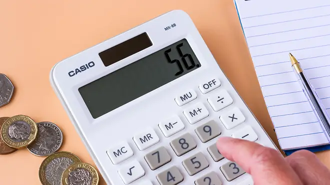 White calculator alongside UK pound coins
