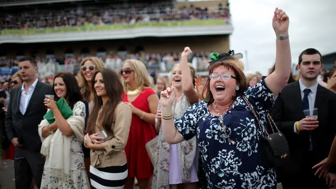 Racegoers cheer on their horses as they enjoy the atmosphere of Ladies Day at the Aintree Grand National Festival