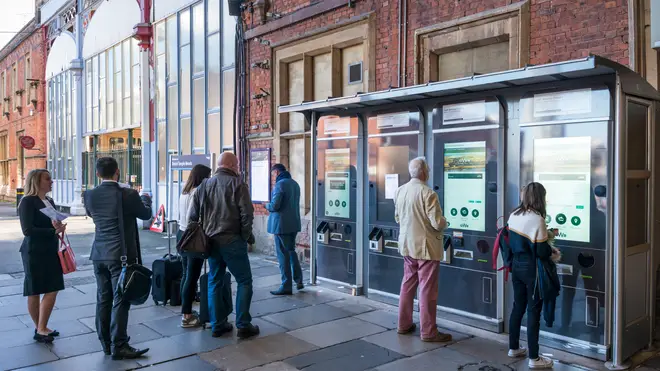 Passengers queue at self-service ticket machines