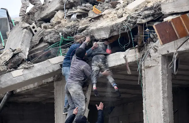 Residents retrieve an injured girl from the rubble of a collapsed building following an earthquake in the town of Jandaris, in the countryside of Syria's northwestern city of Afrin.