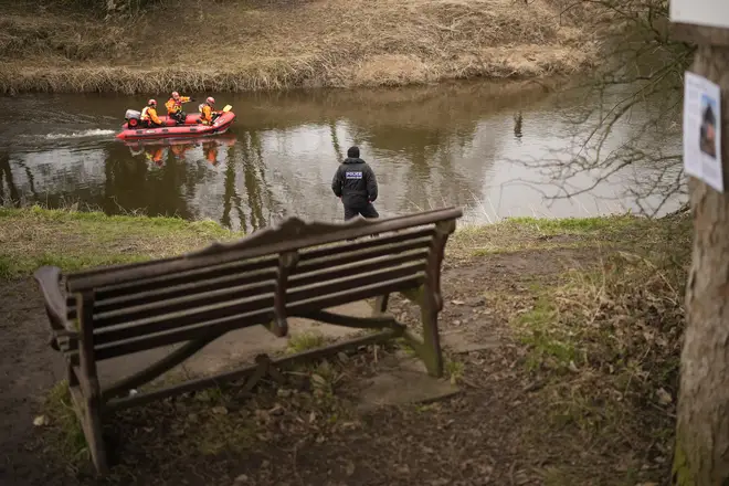 A search dog from Lancashire Police and a crew from Lancashire Fire and Rescue service search the River Wyre for missing woman Nicola Bulley, near the bench where her mobile phone was found.
