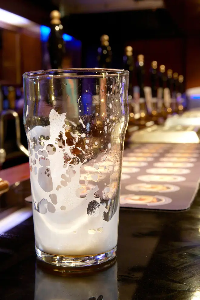 An empty pint glass on a bar