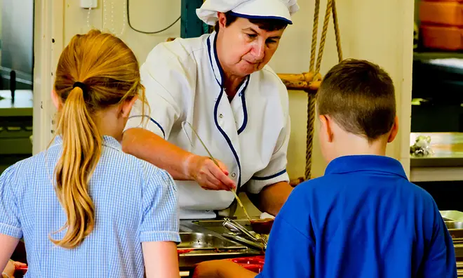 Dinner lady serving pupils lunch at school