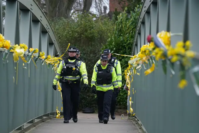 Police officers walk past yellow ribbons and messages of hope tied to a bridge for Nicola Bulley over the River Wyre