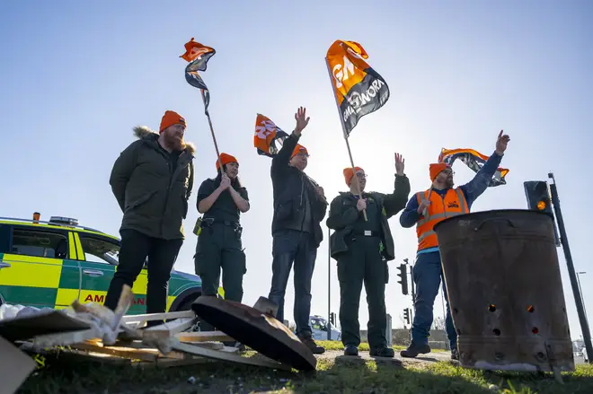 Paramedics and GMB Union representatives wave flags to motorists during industrial action on February 6, 2023