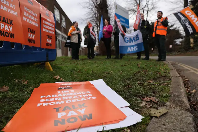 Ambulance workers from the GMB Union hold flags as they form a picket line outside Walton Ambulance station, in south-west London on February 20, 2023.