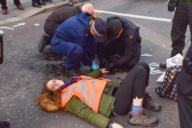Police officers dissolve the glue on a protester's hand on Bishopsgate