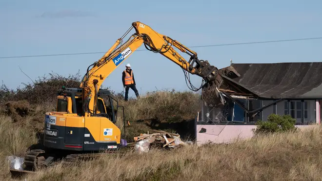 A digger demolishes the house, which would have fallen into the sea otherwise