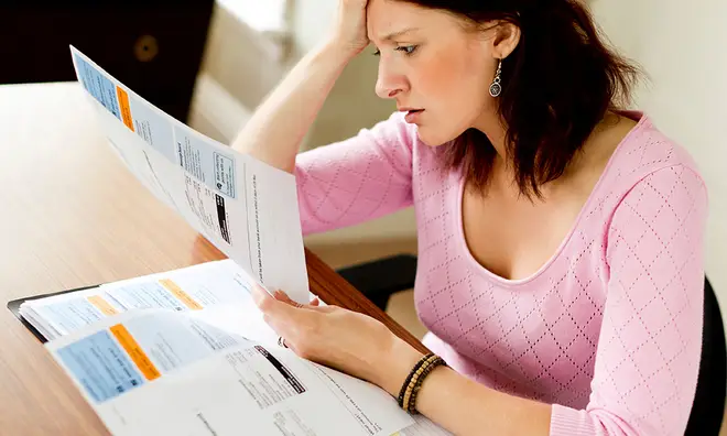 Woman looking worries as she reads her energy bills