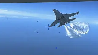 A Russian Su-27 approaching the back of the MQ-9 drone and beginning to release fuel