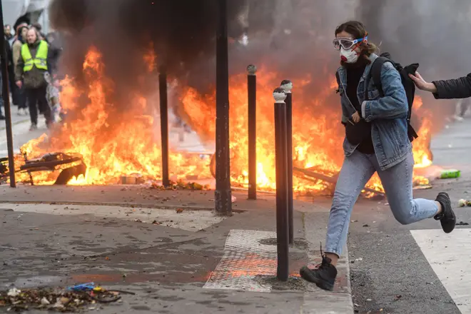 A protester runs past a fire set in the street in Paris