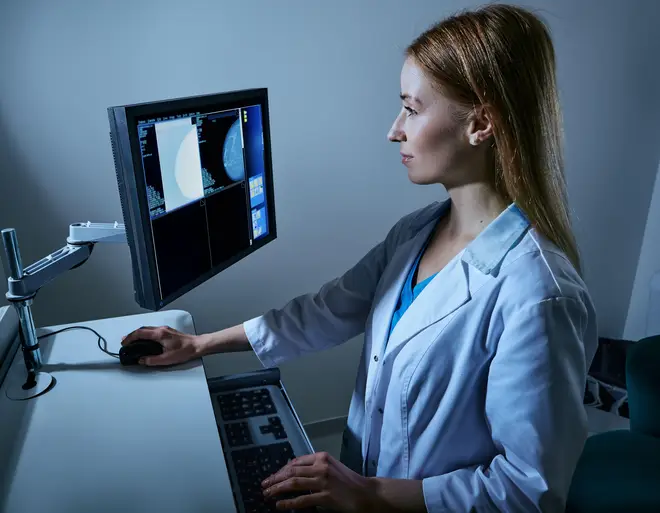A medical technician performing a mammogram