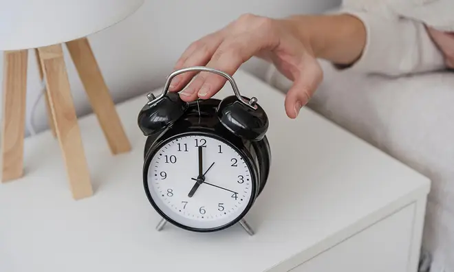 Hand turning off bedside alarm clock