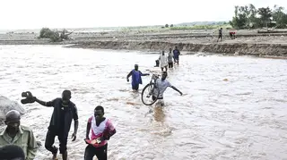 People wade through floodwaters caused by Tropical Cyclone Freddy in Malawi
