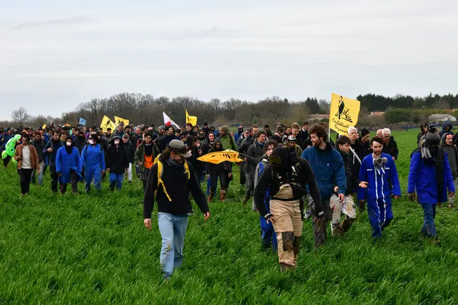Protesters walk in a field during a demonstration against the construction of the reservoir.