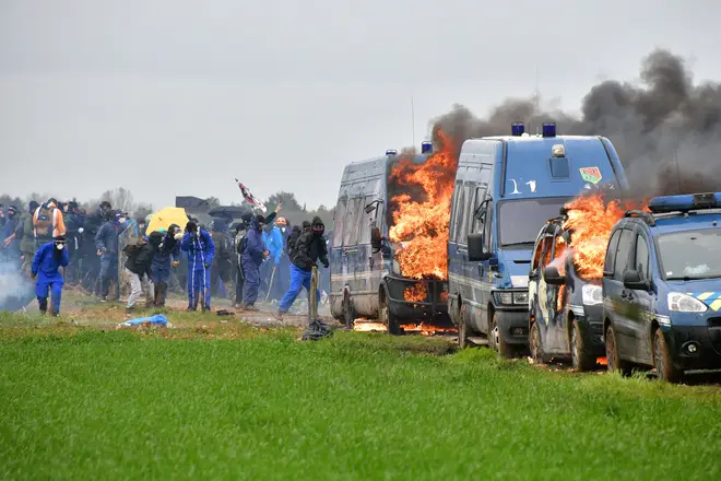 Protestors stand next to French gendarmes' burning cars