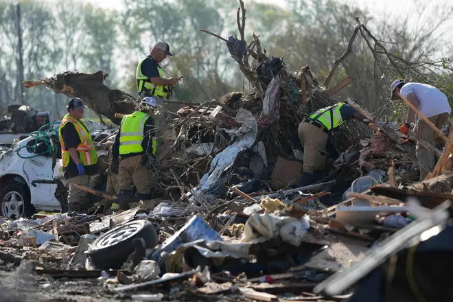 Emergency rescuers and first responders climb through a tornado demolished mobile home park looking for bodies that might be buried in the piles of debris, insulation, and home furnishings