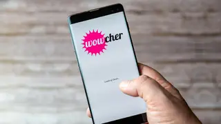 A Mobile phone being held showing the Wowcher app open on screen