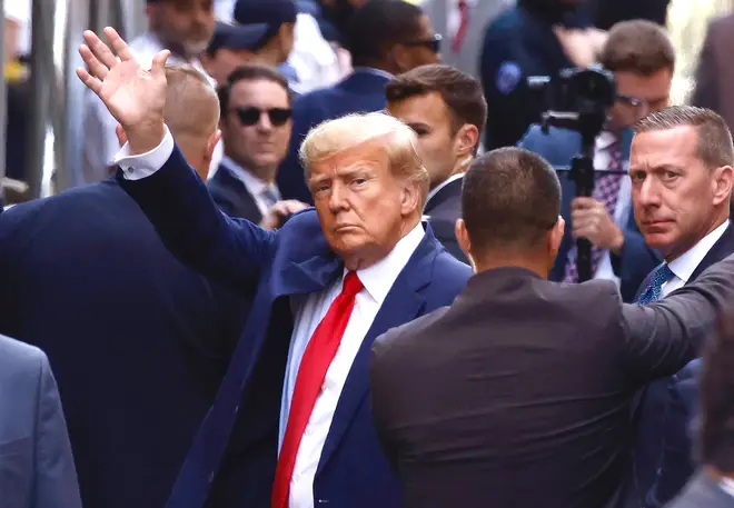 Mr Trump waves as he arrives at court