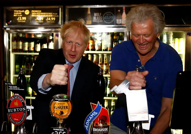 Boris Johnson (L) pulls a pint of Windsor & Eton brewery&squot;s "Knight of the Garter" beer as he talks with JD Wetherspoon chairman Tim Martin