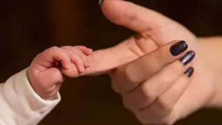 A baby holding a mother's finger