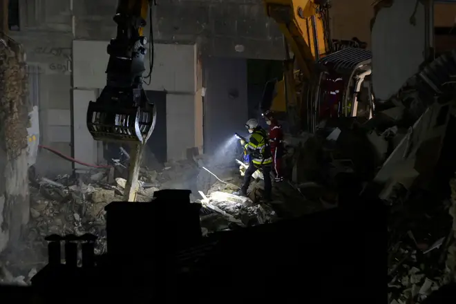 Emergency service personnel shine torches into the rubble Rue de Tivoli 