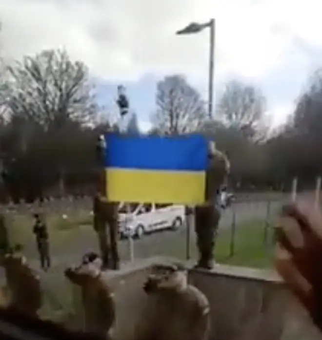 Well-wishers hold up a Ukrainian flag as the recruits depart.