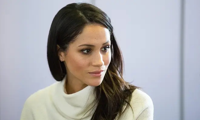 Meghan Markle wearing white polo jumper and not smiling