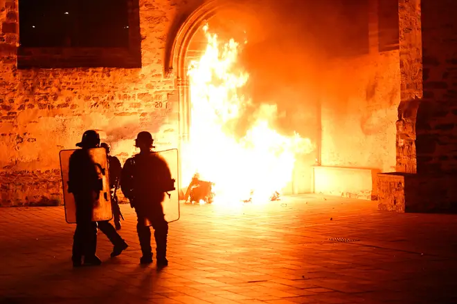 French anti-riot police officers stand next to a fire in Rennes