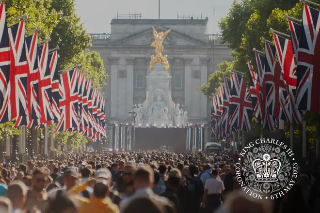 A crowd packed Mall looking towards Buckingham Palace which is aligned with Union Jack flags