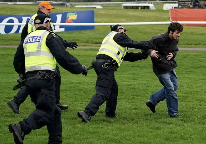 A protester is grabbed by officers at Ayr Racecourse