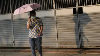 A woman holds an umbrella to shelter from the sun in Bangkok, Thailand