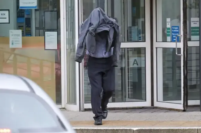 Civilian police worker Timothy Schofield covers his head as he leaves Exeter Crown Court