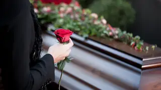 A woman holding a rose at a funeral