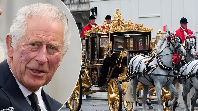 King Charles wearing a black suit and waving alongside the Diamond Jubilee Coach which he has chosen for his coronation day